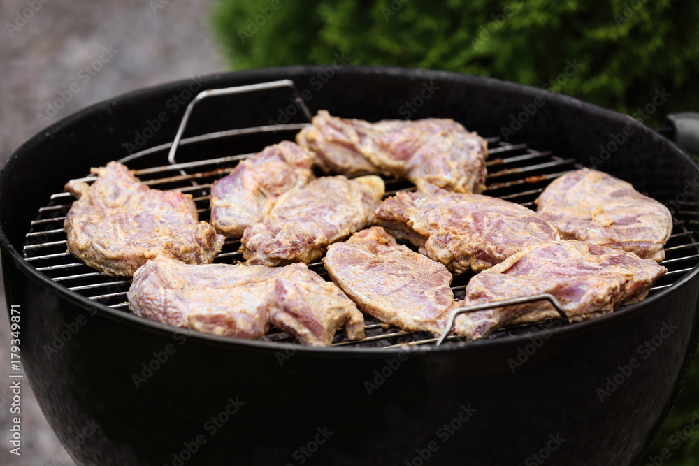 Raw meat cooking on barbecue grill, outdoors Raw meat cooking on barbecue grill, outdoors