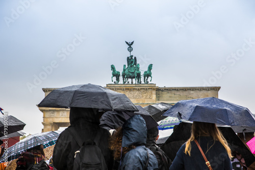 Touristen mit Regenschirmen vor Brandenburger Tor in Berlin