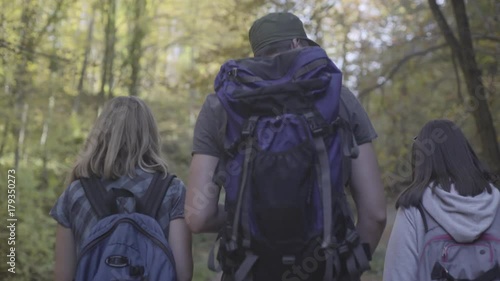 Wallpaper Mural Overhead steady cam tracking shot of young adults, man and two woman with backpacks and trekking poles during hiking through the deep forest in blurred background, autumn season, Torontodigital.ca