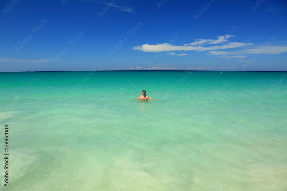 Aruba island. Man standing in the ocean. Turquoise color water of ocean and blue sky. September, 2017