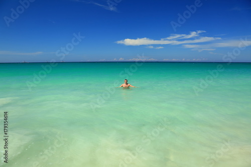 Aruba island. Man standing in the ocean. Turquoise color water of ocean and blue sky. September, 2017