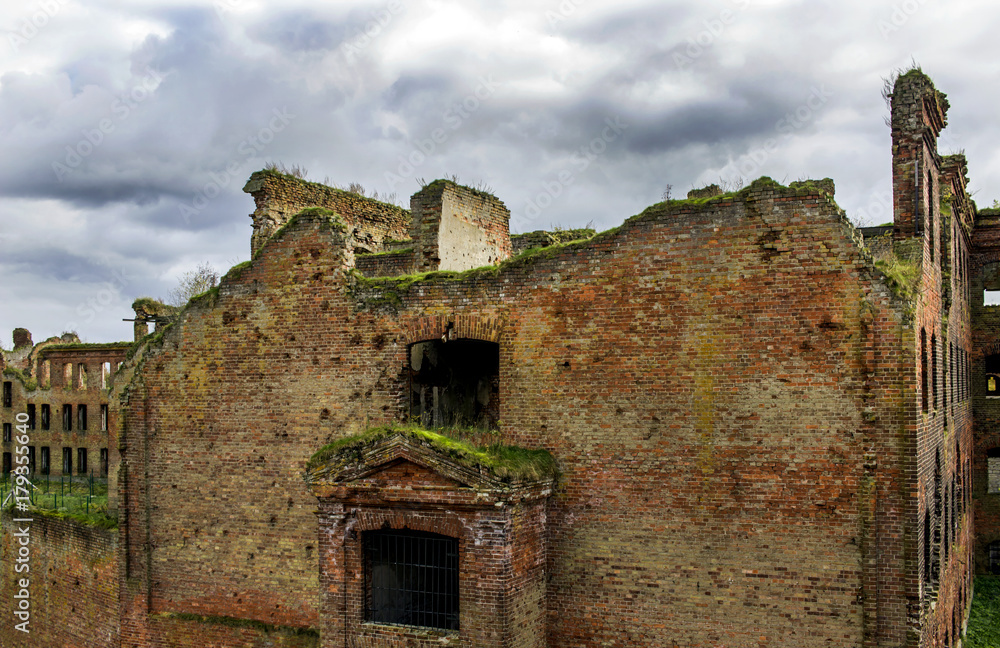 A war-torn building of red brick, broken windows, gloomy sky. The concept of the consequences of war and destruction. Northern Europe. Ruins of an old prison. A war-torn building of red brick, broken windows, gloomy sky. The concept of the consequences of war and destruction. Northern Europe. Ruins of an old prison.