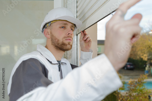 Contractor looking at window roller shutter photo