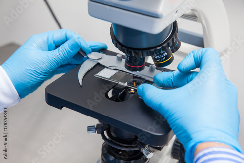 Canvas Print Young male scientist looking at slides under the microscope