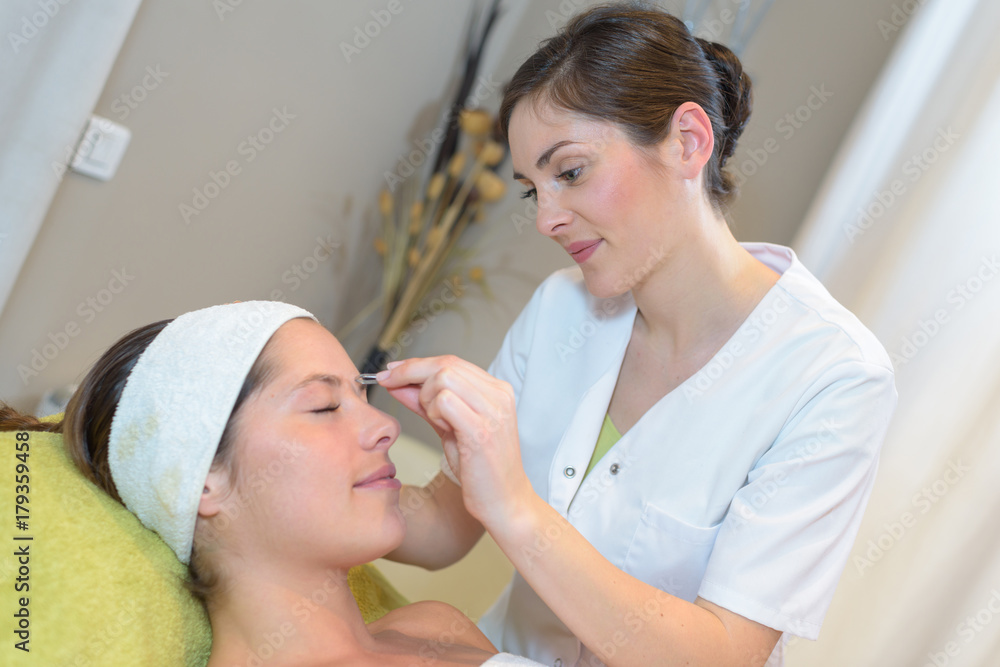 cosmetologist applying permanent make up on eyebrows