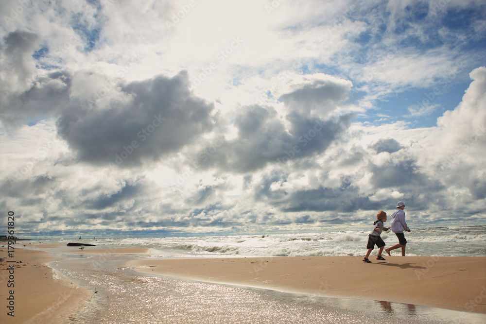 Children running on the beach on a cloudy windy day