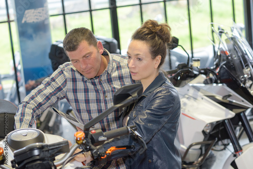 positive couple buying a motorbike in workshop