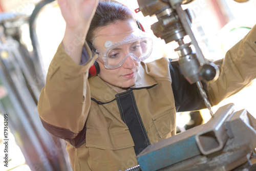 Foto beautiful brunette factory worker drilling a piece