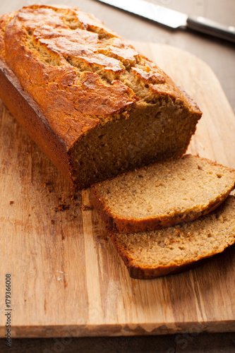  Freshly baked pumpkin bread loaf on cutting board with knife on dark wood background vertical shot 