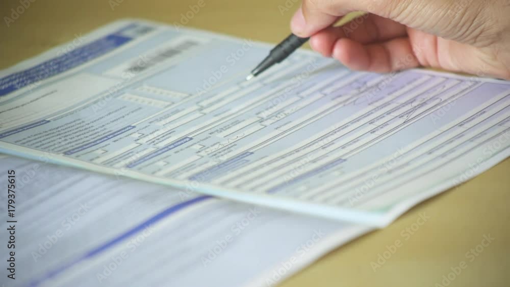 Close-up of a hand of a man completing an official form and signing it. A man filling in a document Close-up of a hand of a man completing an official form and signing it. A man filling in a document