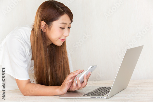 ノートパソコン・スマートフォンを操作する女性