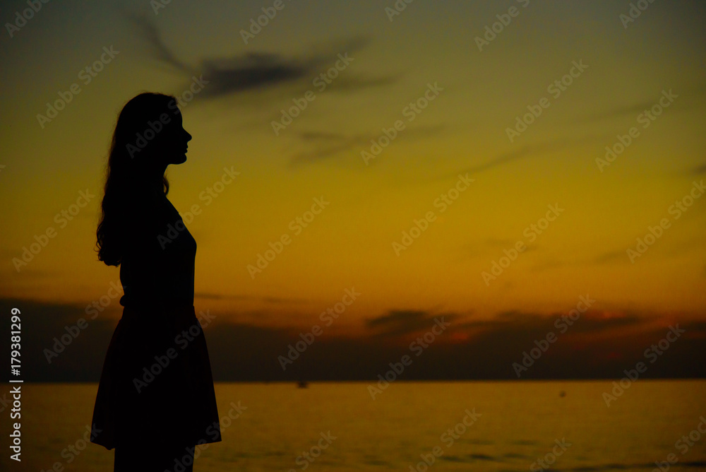 Lonely girl watching sunset near the sea or ocean