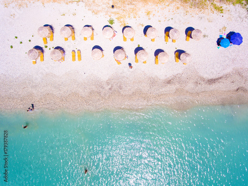 Summer beach in Lefkada Greece with sun umbrellas and sunbeds and clear blue waters aerial view photo