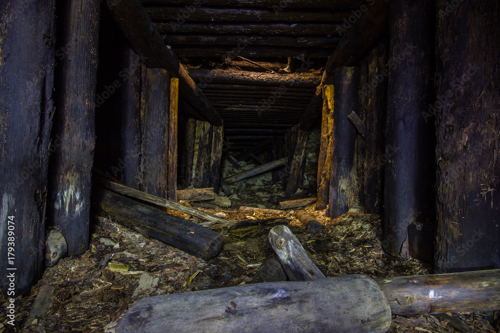 Abandoned old chromite mine shaft tunnel with wooden timbering