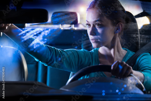 Portrait of a young woman driving her car at night in the rain