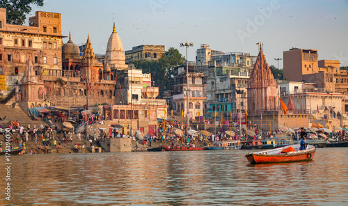 Ancient Varanasi city with old architectural buildings and temples along the Ganges river ghat as viewed from a boat.
