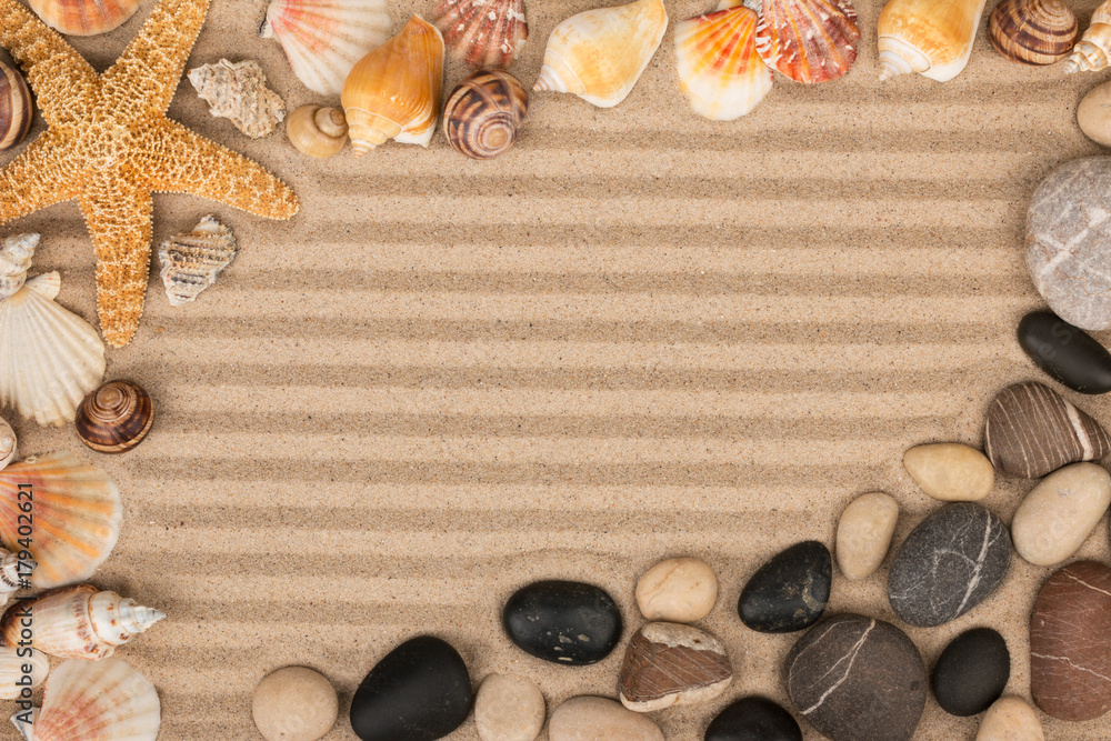 Obraz premium Frame made of sea shells, stars and stones lying on striped sand.