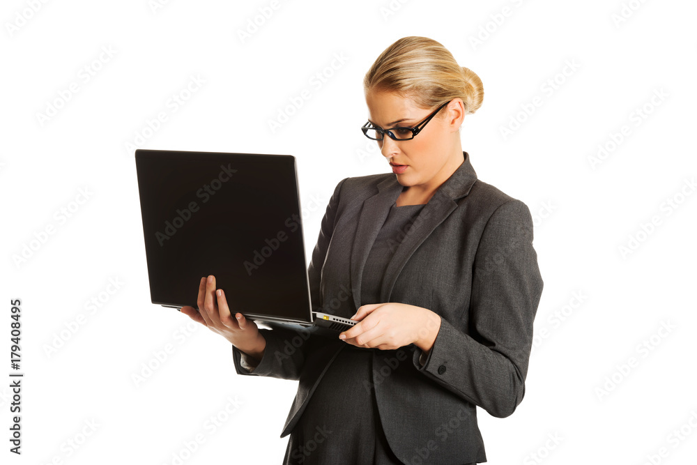 Businesswoman standing and holding a laptop Businesswoman standing and holding a laptop