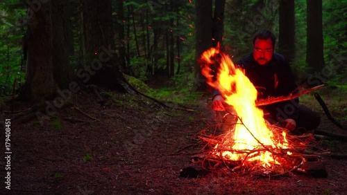 Young man camper sitting by the campfire. slow motion video
