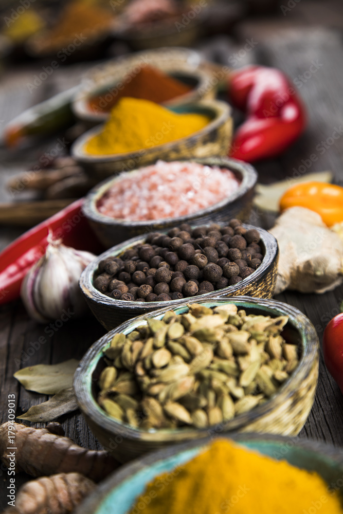 A selection of various colorful spices on a wooden table in bowls A selection of various colorful spices on a wooden table in bowls