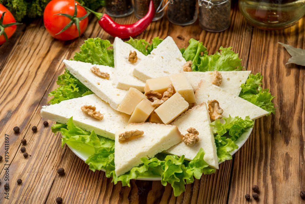 Homemade soft cheese Suluguni with tomatoes, paprika, onions and fresh basil on a wooden board