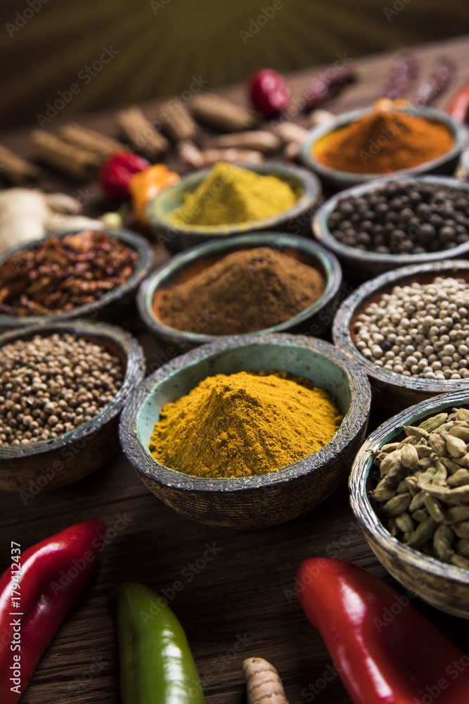 A selection of various colorful spices on a wooden table in bowls A selection of various colorful spices on a wooden table in bowls