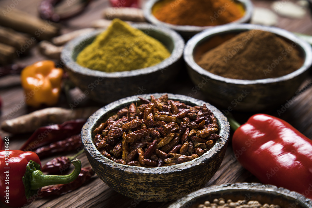 A selection of various colorful spices on a wooden table in bowls