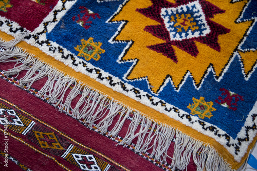 Colourful hand woven berber carpets spread on the bazaar floor in Morocco © CharnwoodPhoto