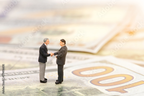 miniature people  shecking hand on us dollar banknote,business concept photo