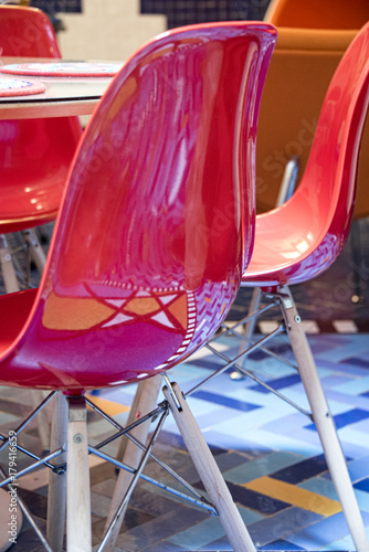 Red plastic chair ouside of cafe reflecting star deisgn in floor mosaic photo