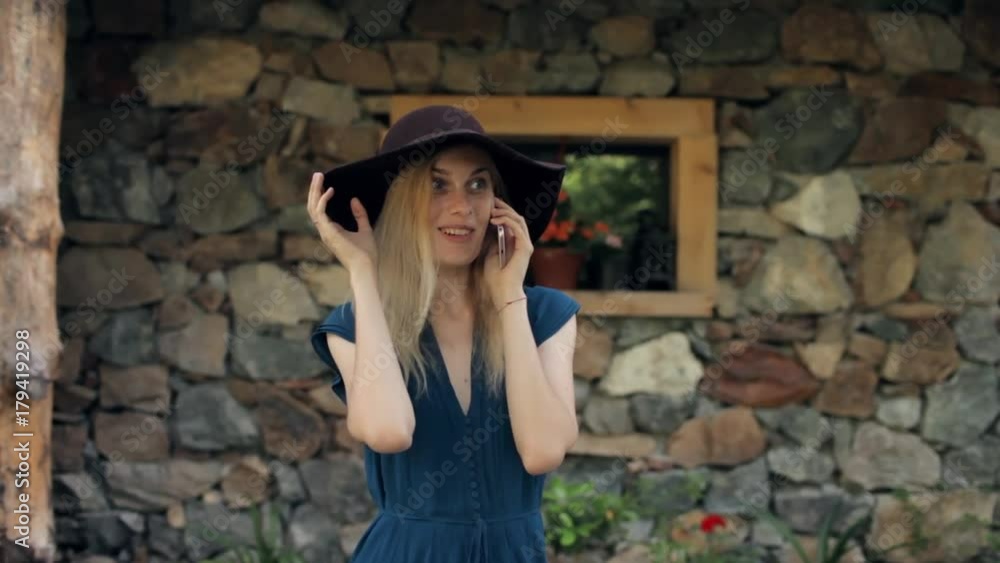 beautiful girl talking on the phone on the background of an old stone house beautiful girl talking on the phone on the background of an old stone house