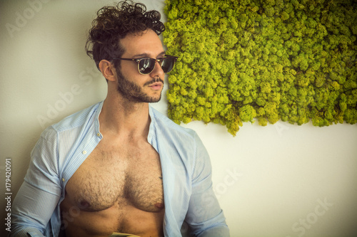 Fotografija Shirtless sexy male model lying alone on couch in his living-room, looking away
