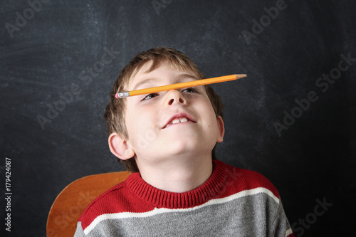 Young bored boy balancing a pencil on his nose.