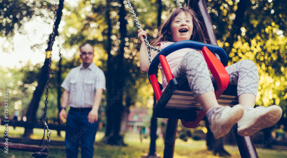 Fototapeta premium Portrait of man and girl with down syndrome swinging