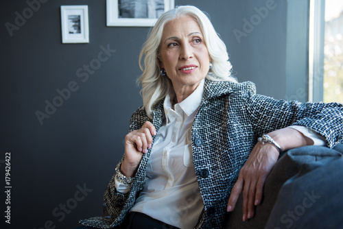Photos Charming positive senior woman is relaxing on sofa