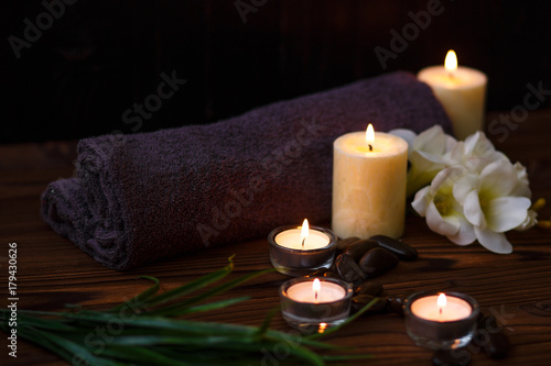 A candle in a glass vase  decoration and various interesting elements on a dark wooden background. Candles burning. Set for spa and massage. stones for massage