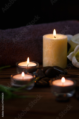 A candle in a glass vase  decoration and various interesting elements on a dark wooden background. Candles burning. Set for spa and massage. stones for massage