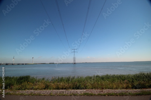 High voltage power line high above a lake in Netherlands with blue sky