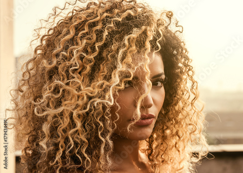 Beautiful woman with gorgeous curly hair in the sunlight