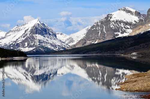 Schilderij op canvas Many Glaciers snow covered mountain and landscape reflecting off of Swiftcurrent
