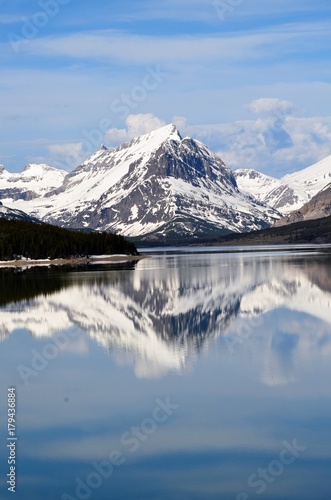 Many Glaciers snow covered mountain and landscape reflecting off of Swiftcurrent lake in Montana, USA