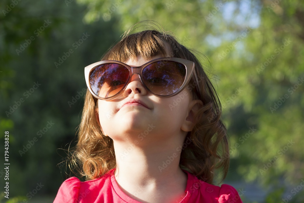 little girl, fashionable in big mom's glasses. happy child