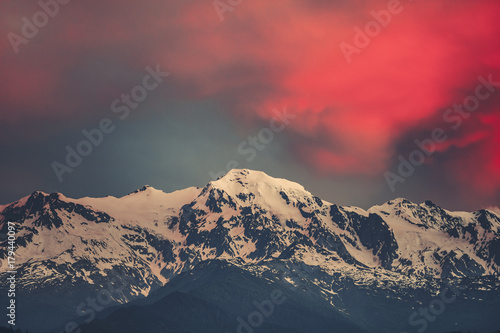 Beautiful sunset over the snowy mountain peak. Nature landscape scene. Dramatic overcast red sky. Holidays  travel  sport  recreation. Main Caucasian ridge  Svaneti  Georgia. Retro toning filter