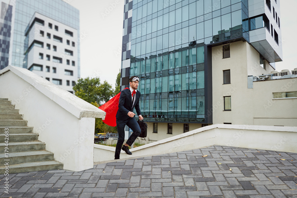 A businessman hurries up the stairs against the background of business buildings.
