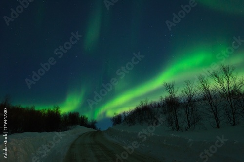 Aurora Northern lights over the hills and road.