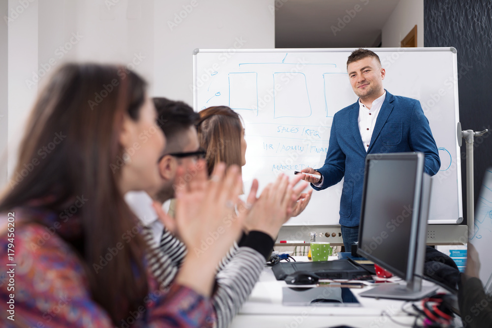 Young business people applauding to their colleague after successful presentation on a meeting