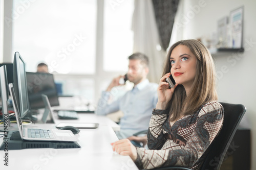 Portrait of beautiful confident young businesswoman talking on the phone while working in her office