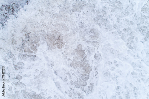 Texture of a sea foam rolling on a sandy beach