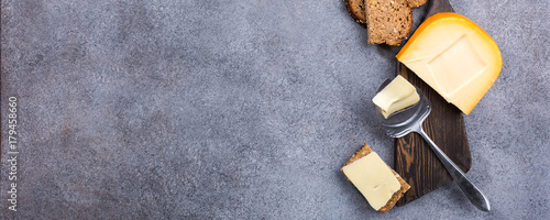 Obraz na plátně Delicious dutch gouda cheese with cheese slices, multigrain bread and special knife on old wooden board