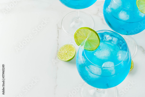 Alcohol drink. Glasses with a blue alcoholic cocktail with ice and lime garnish. Blue Curacao. Liquor. Copy space